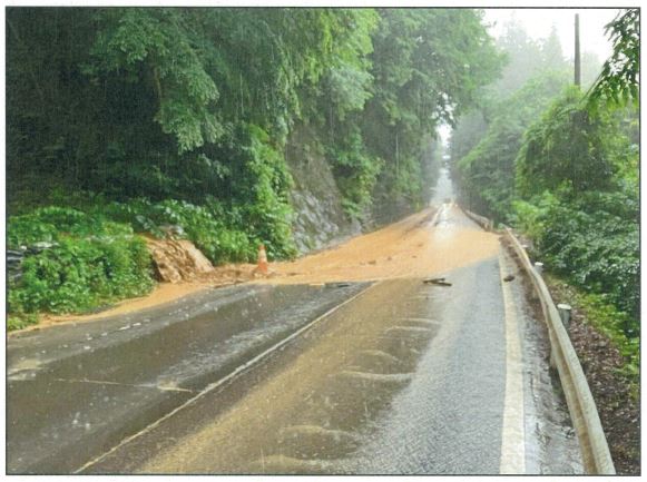 県道へ流れ出した泥水が道路いっぱいに広がっている写真