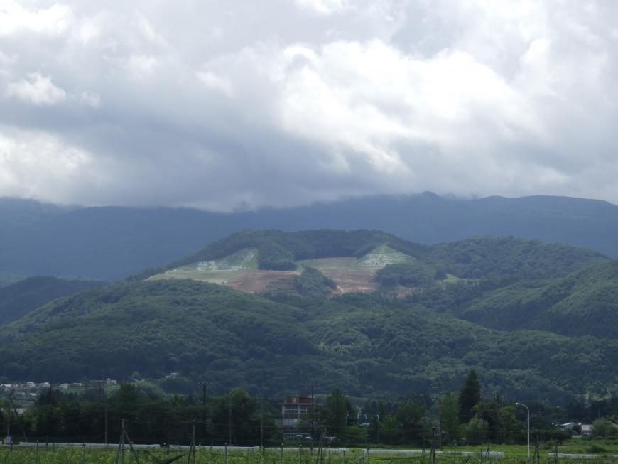 山脈の上に厚い雲がかかっており、その下に先達山が写っている写真