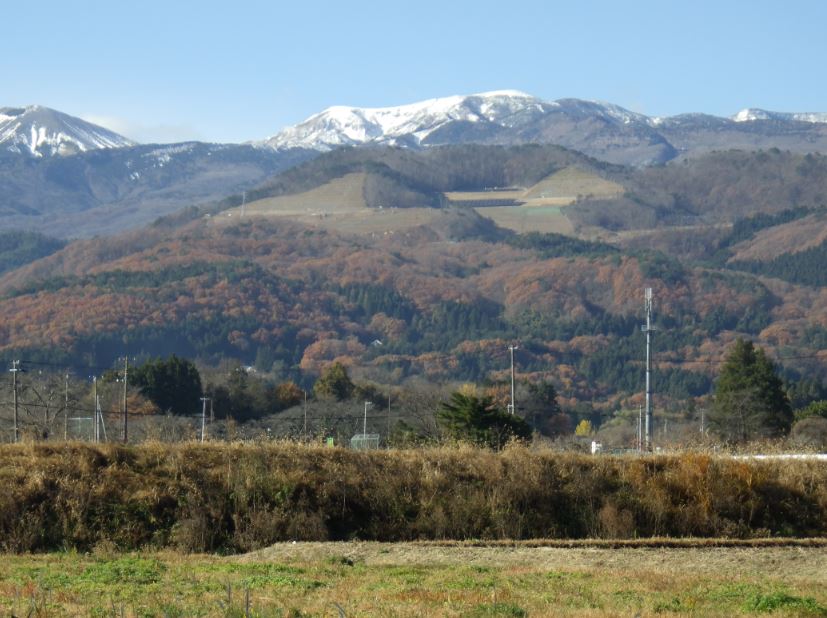 少し紅葉した先達山と山頂付近に雪が積もって白くなっている山々の写真