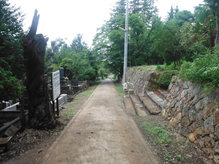真っ直ぐに伸びた道の右側に石積み塀と階段がある御山墓地周辺の写真