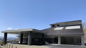 大きな屋根づくりで広い入口付近に、雨除け付きの降車スペースが設けられた福島市葬祭場の写真