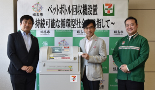 赤羽様、木幡市長、宮内様がペットボトル自動回収機の横に並び写っている記念写真