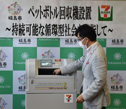 ペットボトル自動回収機の投入口が開き市長が投入している様子を写した写真