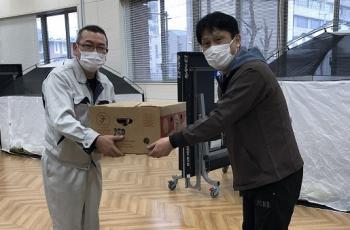 市の職員の男性に段ボール入りの食料品を手渡ししているヨークベニマルの職員の男性の写真