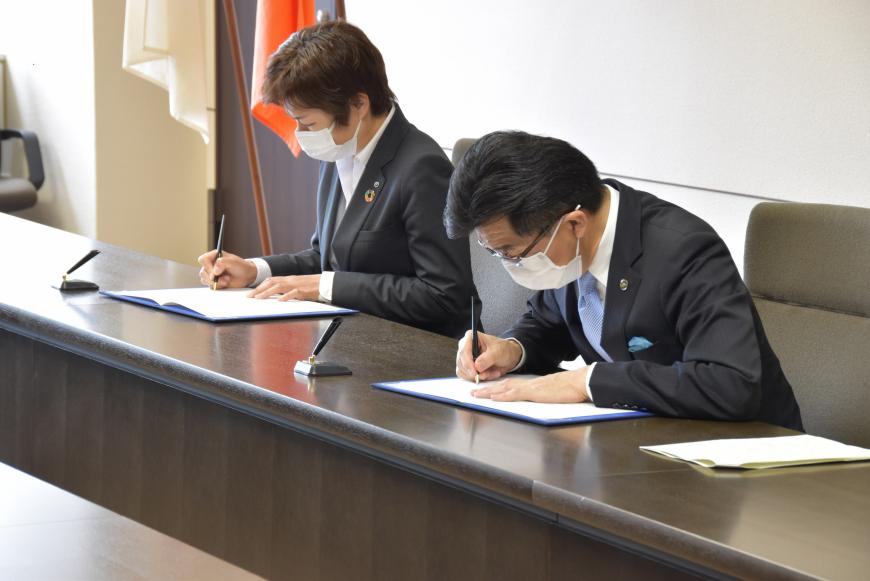 山貫支店長と木幡市長が協定書にサインをしている写真