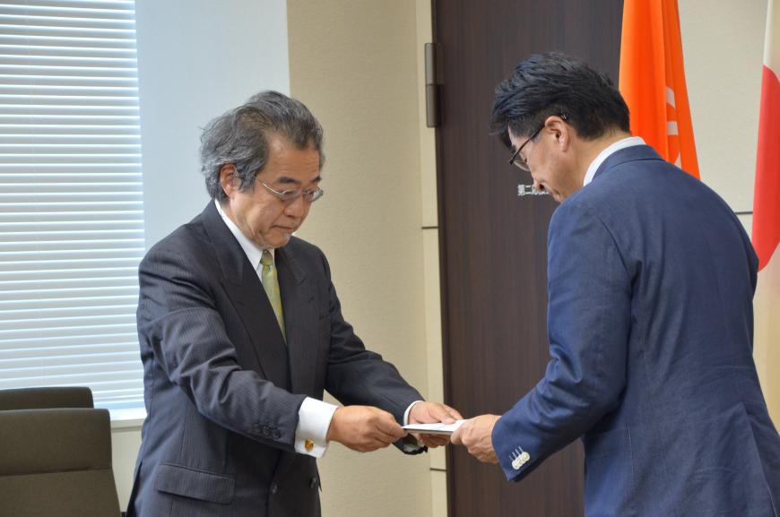 委員会代表の男性が市長に提言書を手渡している様子の写真