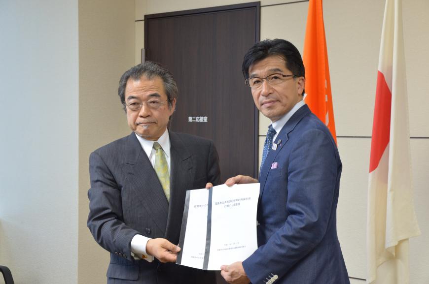 提言書を開いて一緒に持ってカメラに向かって見せている委員会代表の男性と市長の写真