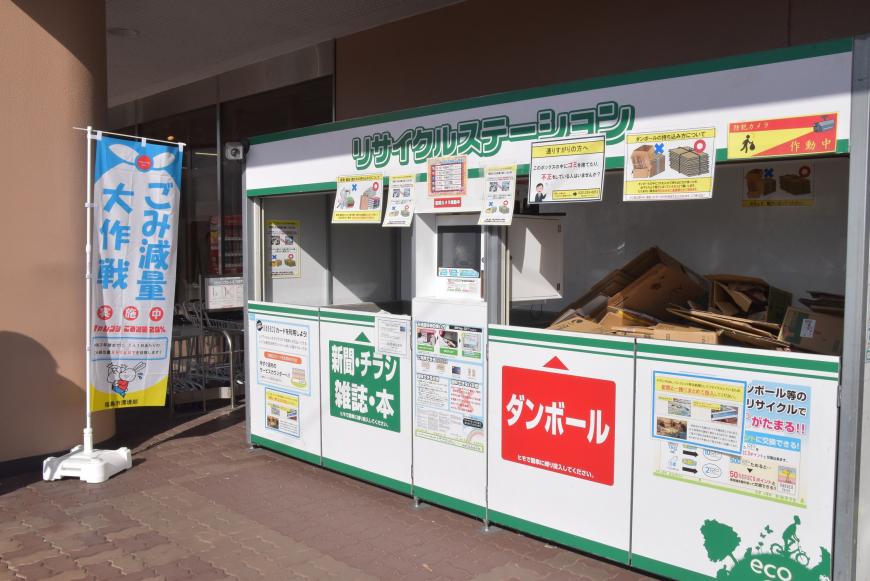 ごみ減量大作戦の幕の横に設置された資源物回収BOXにたくさんの段ボールが回収されている写真