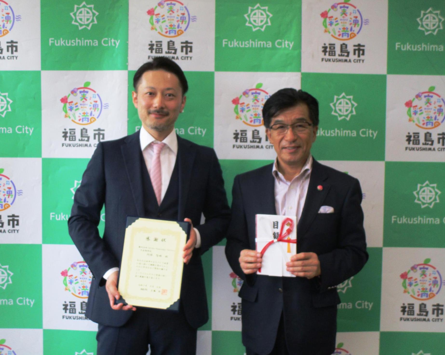 企業版ふるさと納税の感謝状贈呈の写真です。左に株式会社SaCuRa Knowledge Factoryの阿部社長、右に市長が写っています。