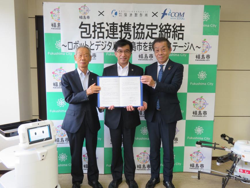 市長を中心に関係者の方々3名で協定書を持ちながら記念撮影をしている写真