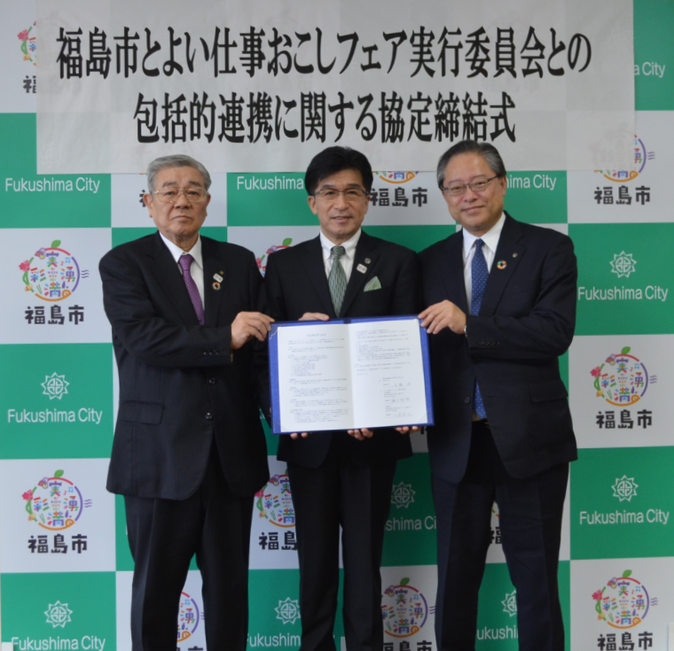福島市とよい仕事おこしフェア実行委員会との包括的連携に関する協定締結式と書かれた幕の前で市長を挟んで2名の理事長が並び締結書を持ち記念撮影をしている写真