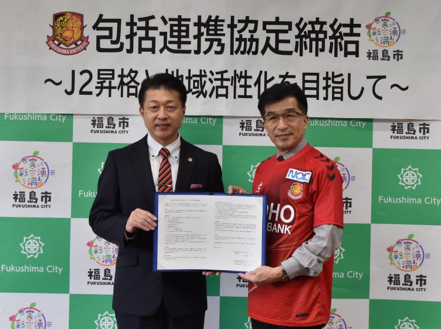 福島ユナイテッドの赤いユニフォームを着た市長と鈴木代表取締役社長が二人で協定書を持ちながら記念撮影をしている写真