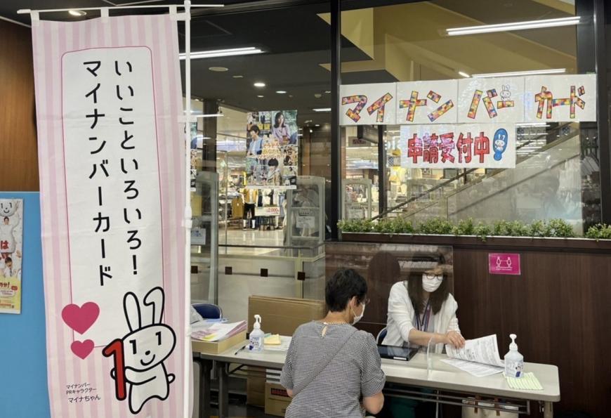 「いいとこいろいろ！マイナンバーカード」ののぼり旗の横に設置されたマイナンバー窓口の写真