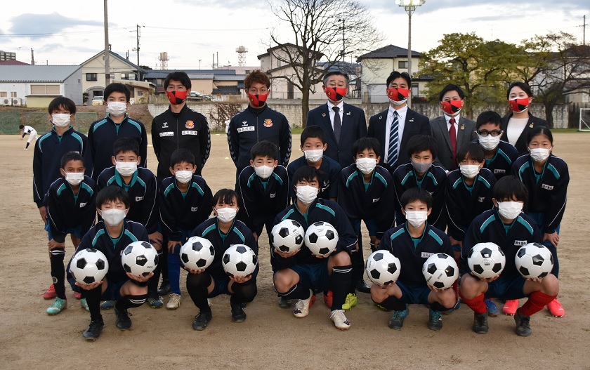 サッカーボール寄贈式でサッカーボールを1列目の子供が持ちながら全員での記念撮影をしている写真