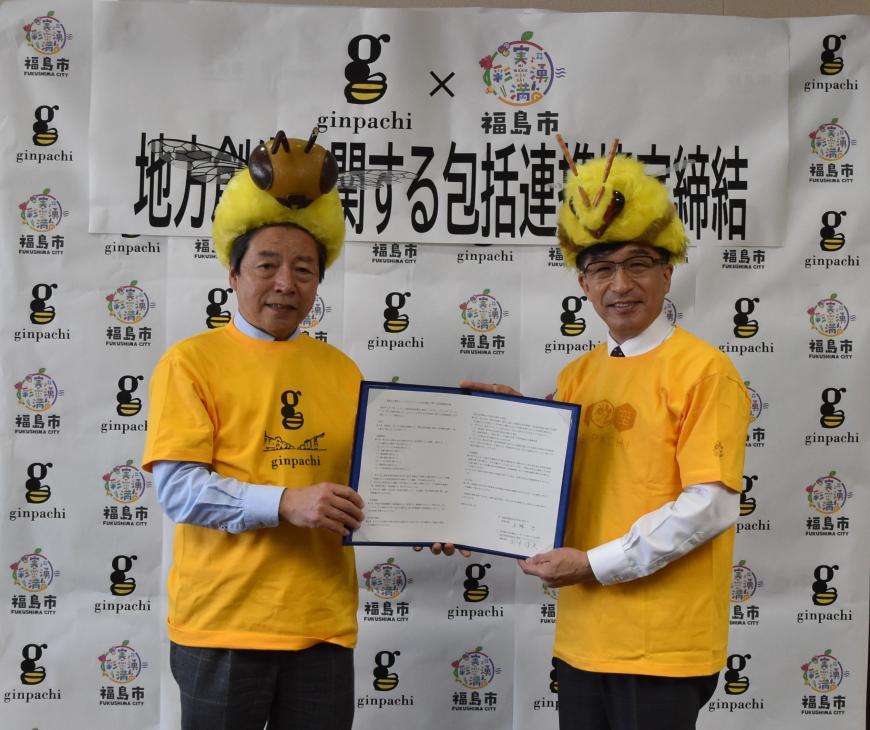 市長と田中副理事長がみつばちの帽子を被って協定書を二人で持ち記念撮影をしている写真