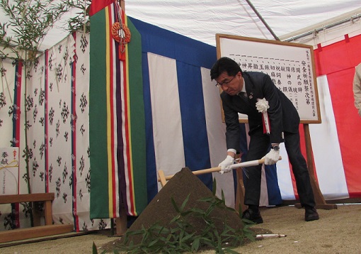 盛砂の上から市長がくわを両手で持ち鍬入れが行われている祈願祭の様子の写真