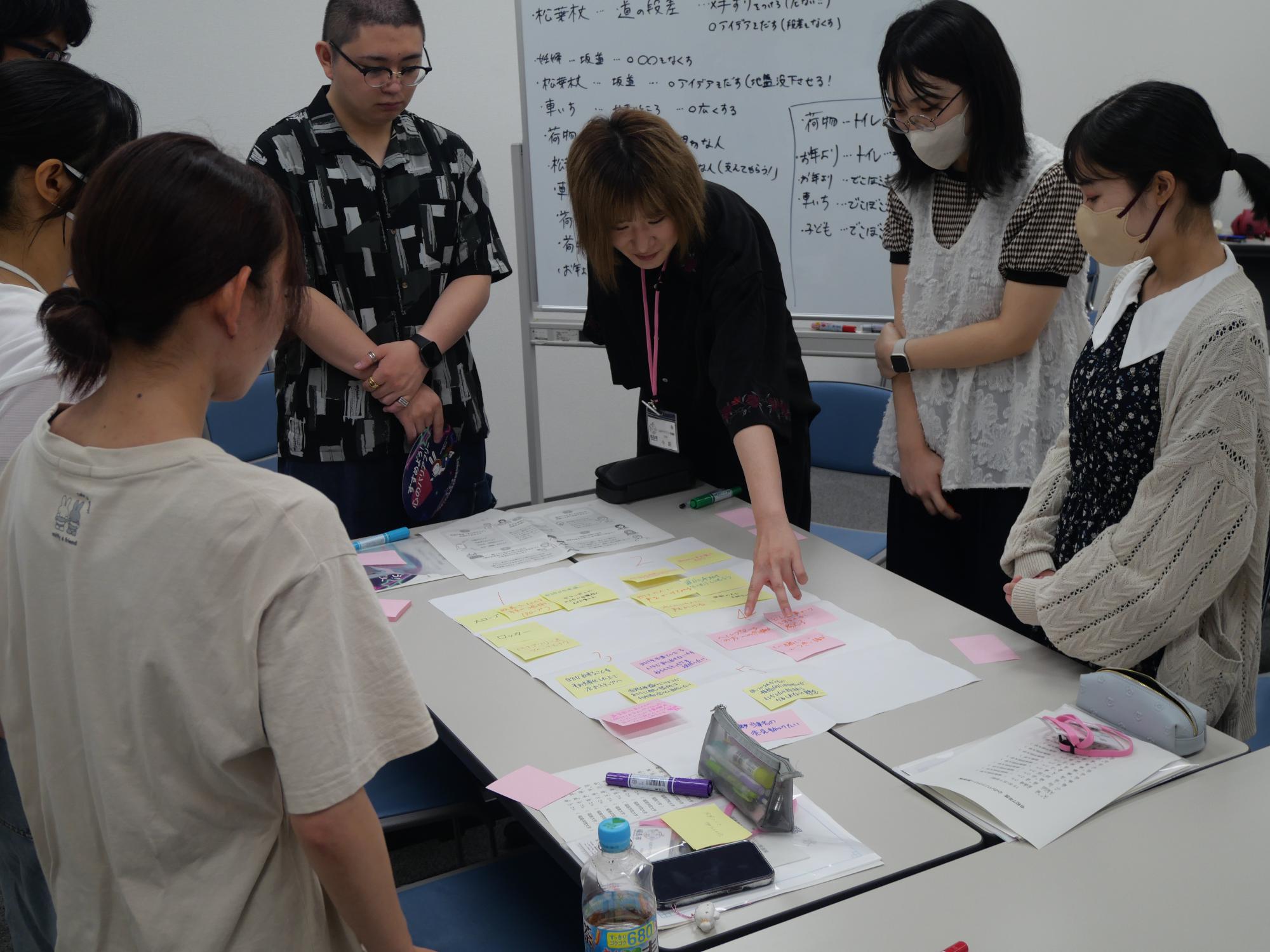 グループディスカッションの様子（女性がふせんを指さす様子）