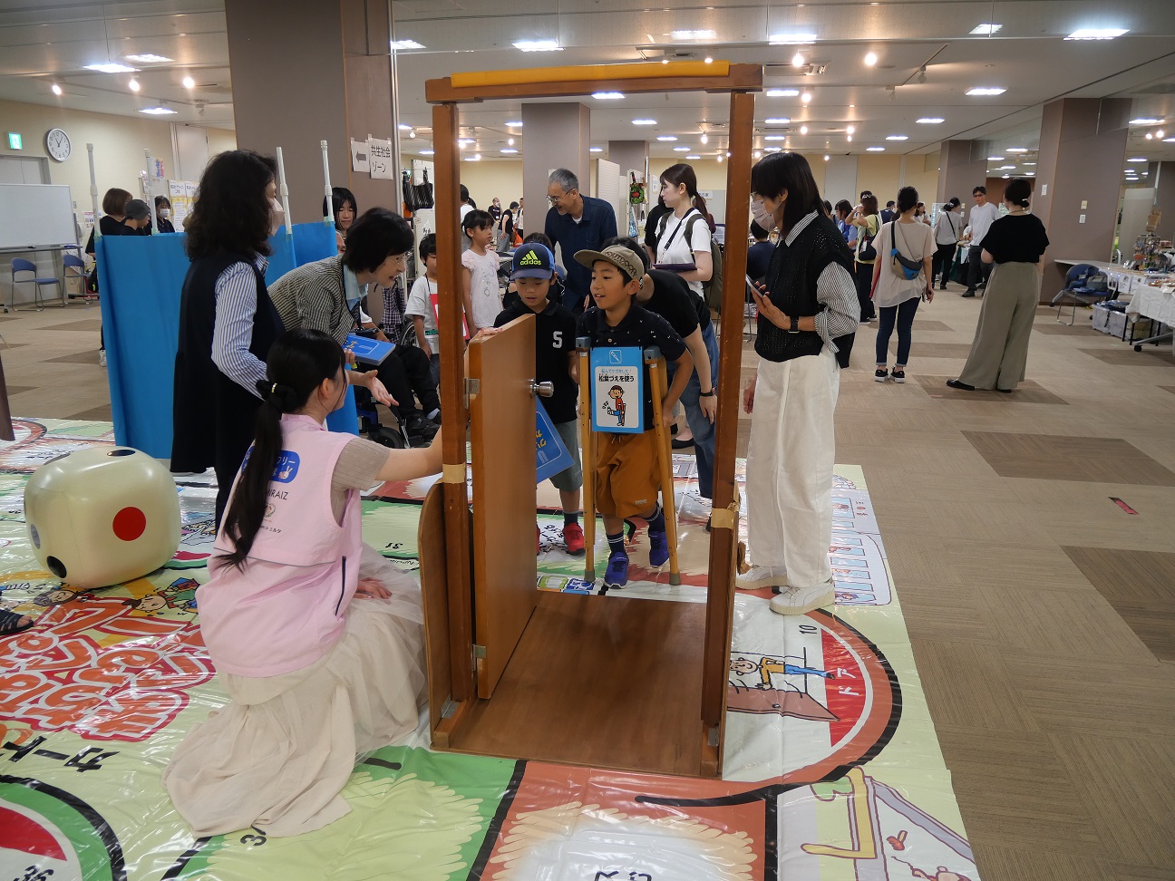 松葉づえをついて扉を開けようとする参加者をサポートする隊員