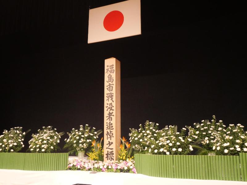 日本国旗が掲げられた福島市戦没者追悼式の会場内の祭壇の写真 令和7年度