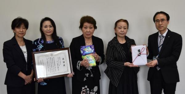 感謝状、生理用品、目録を持って関係者5人の記念写真