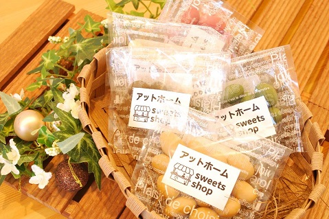 カゴの中に入った透明の袋に「アットホームsweets shop」と書かれたラベルが貼られた5種類のアーモンドチョコレートの商品の写真