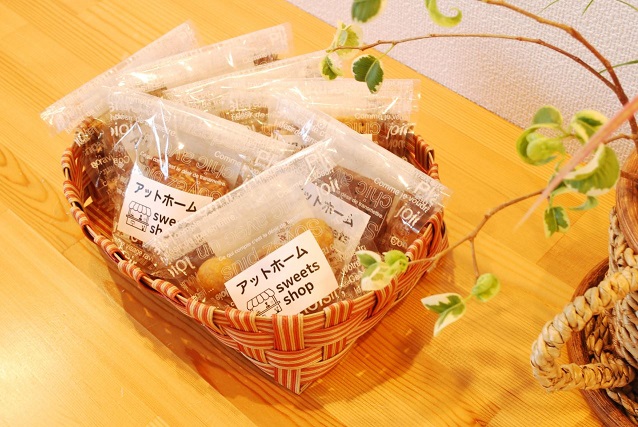 カゴの中に入った透明の袋に「アットホームsweets shop」と書かれたラベルが貼られた7種類のクッキーの商品の写真
