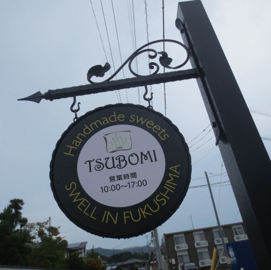 営業時間とアルファベットで店名が書かれた円形の看板の写真