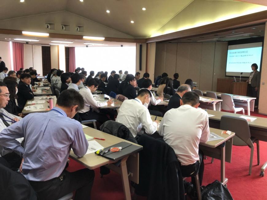 前方に資料が映し出されたスクリーンが設置され、檀上に立つ伊藤講師の話を参加者が聞いている認知症サポーター養成講座の会場の様子の写真
