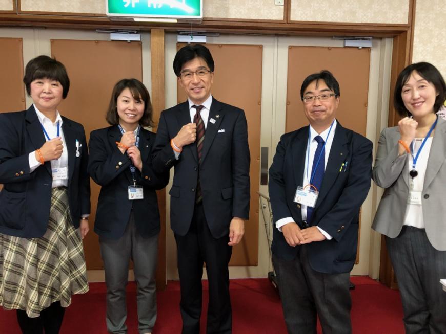 福島市長を中央に手首にオレンジリングを付けた講師の伊藤麻樹子様、長寿福祉課の職員の3名の方々が横一列に並んでいる写真