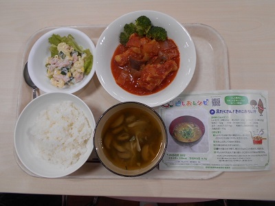 ご飯、汁、鶏肉のトマト煮、マカロニサラダが載ったトレーに適しおレシピのチラシが添えられている写真