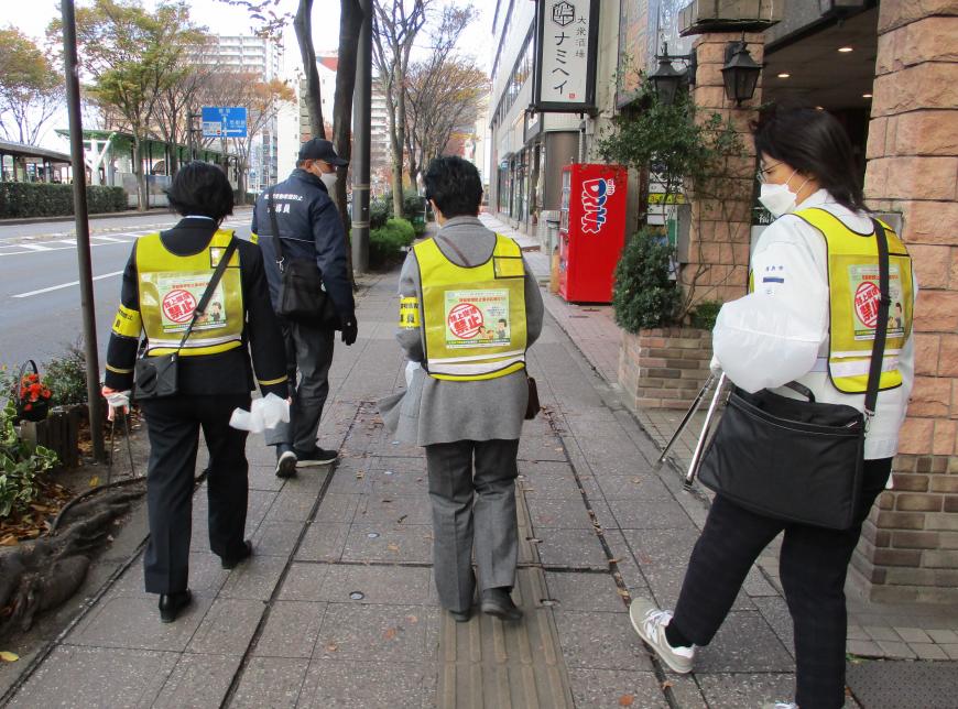 4人の参加者が下を確認しながら歩道を歩いている写真