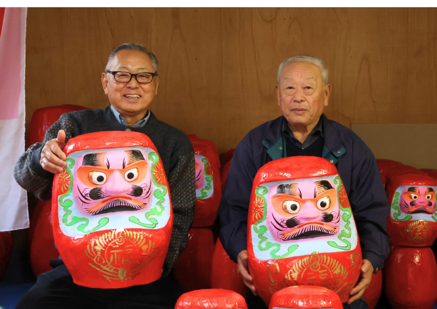 大きなダルマを持ち並んでいる高野会長と村田さんの写真