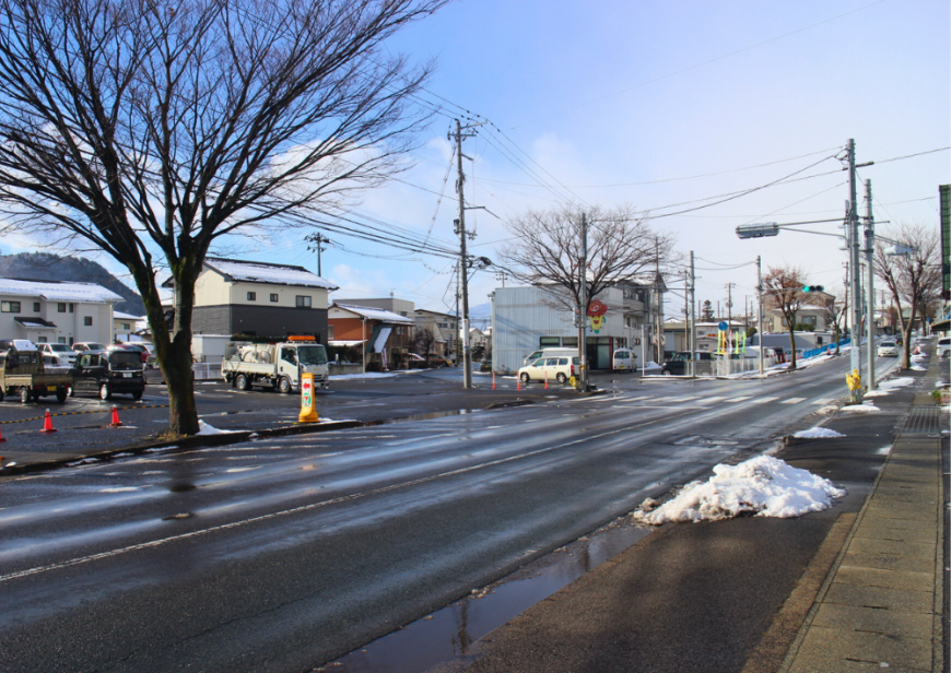 家の屋根や道路の隅に溶けかけた雪が積もった富塚町内の街並みの写真
