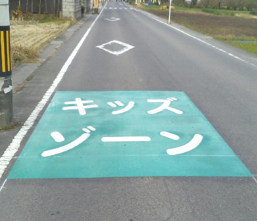 道路の一部分が緑色で塗られ、白い文字で大きくキッズゾーンと書かれた余目保育所前のキッズゾーンの写真
