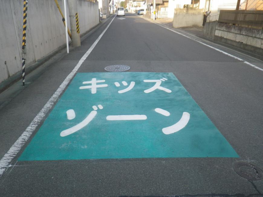 道路の一部分が緑色で塗られ、白い文字で大きくキッズゾーンと書かれた東浜保育所前のキッズゾーンの写真