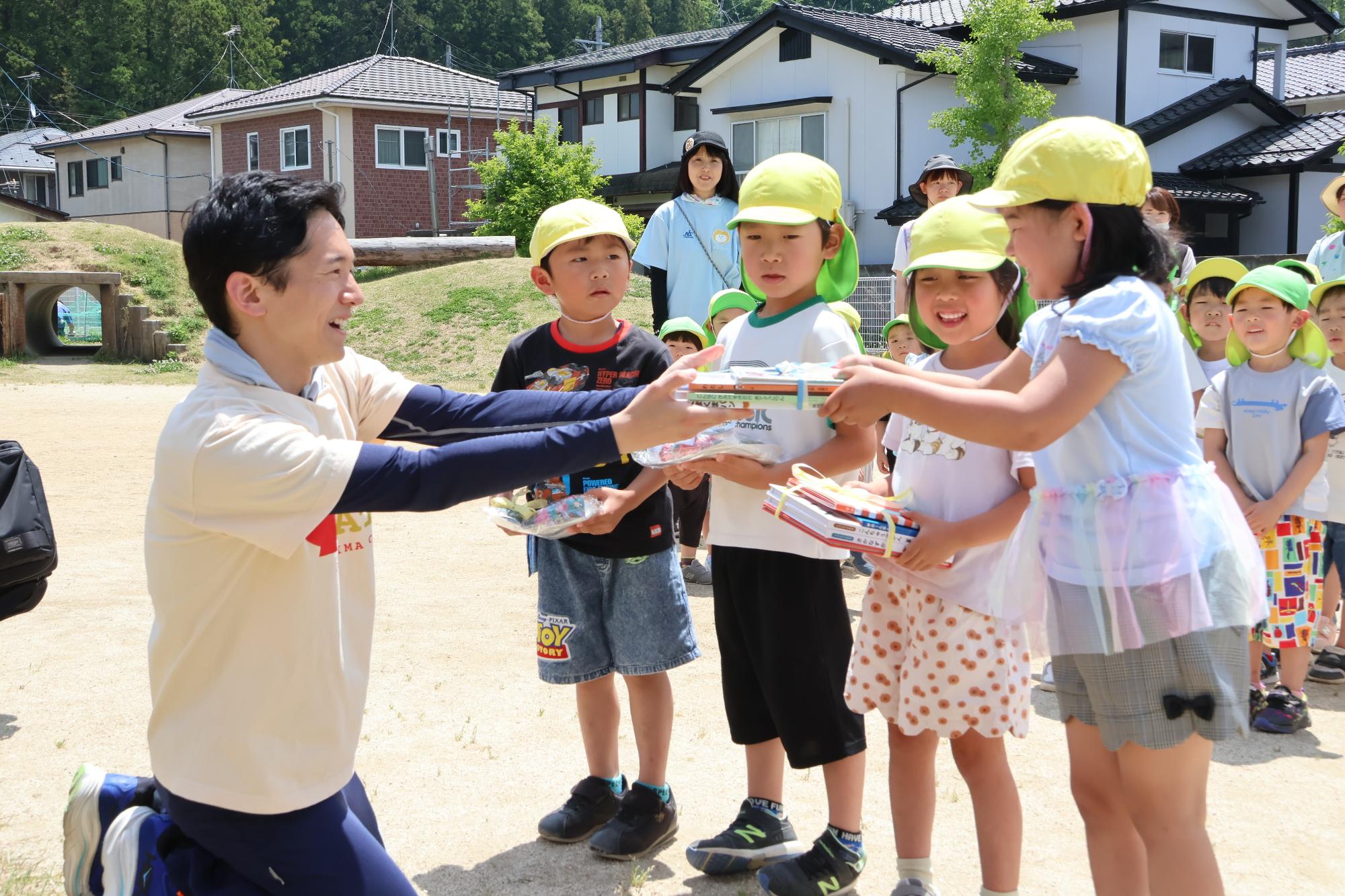 スプーンこども園の園児たちに、福島市長がももりん文庫の絵本を手渡ししている様子。