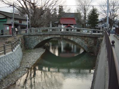 橋の下に川が流れている石積みアーチ橋の写真