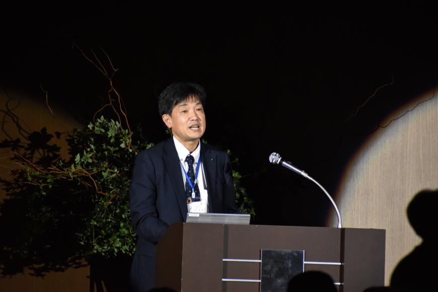 福島市デジタル改革室長の男性が檀上に立ち話をしている様子の写真
