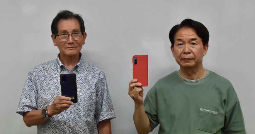 2名の男性がそれぞれスマートフォンを持ち並んでいる写真