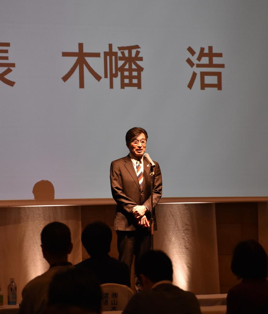 マイクの前に立つ市長が挨拶を行っている様子の写真