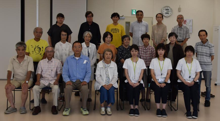 お揃いの白い服を着た3名の講師の方とmDスマホクラブの方々が3列に並んでいる集合写真