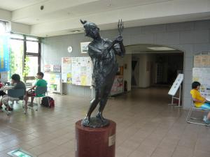 円柱の土台の上に両手でキャンドルの様な物を持ち立っている蓬莱学習センターのホールに展示された作品「キャンドルの祭り」の写真