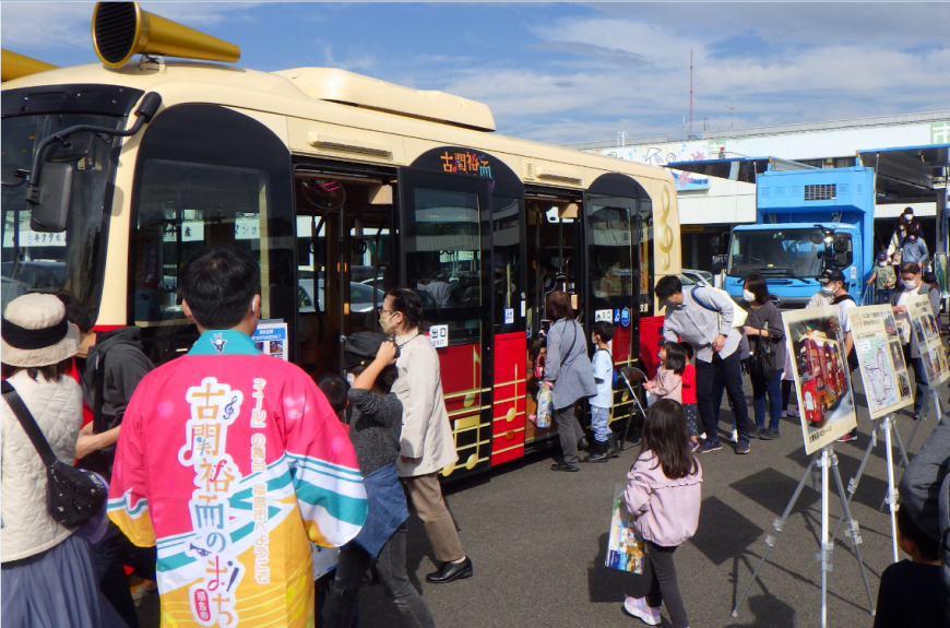 市場まつりの会場に展示されているあかメロディのメロディーバスを多くの来場者が見学にきている写真
