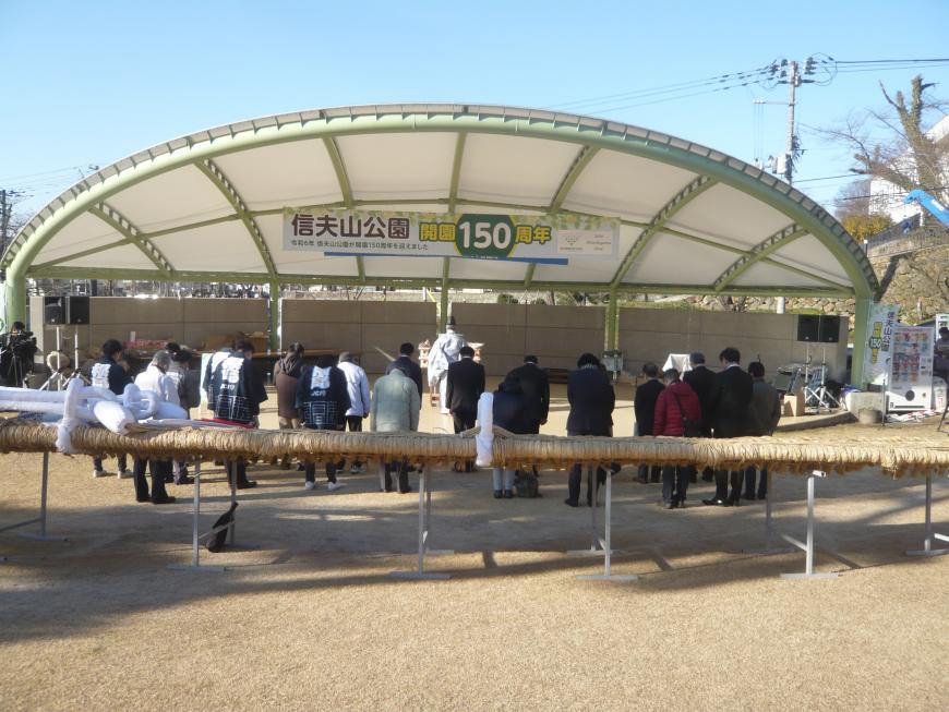 ステージ上にいる宮司の後ろで頭を下げている複数名の関係者たちの写真