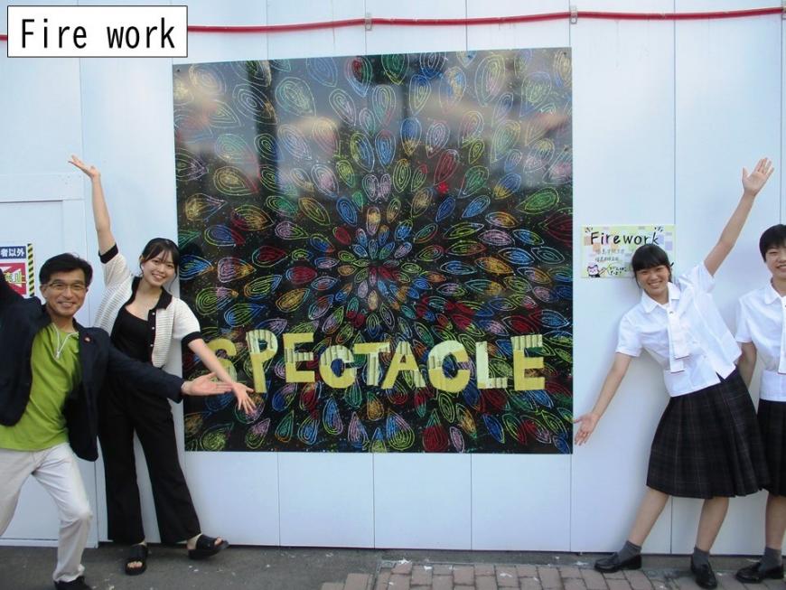 SPECTACLEと書かれたアートの前で3名で絵の両端に立ち両手を斜め上下に伸ばしてポーズをとっている写真