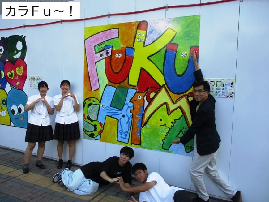 カラFu～の作品の前で寝そべった男の子2名、両手で三角を作っている女子高生、アートの横で両手を広げている男性の写真