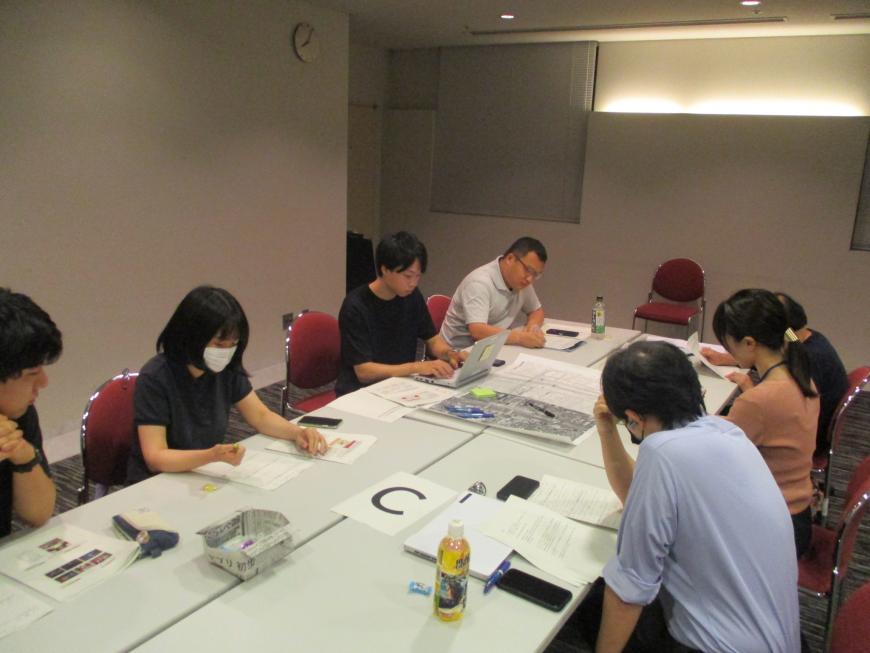 テーブルの資料を見ながら話し合いをしている参加者の写真