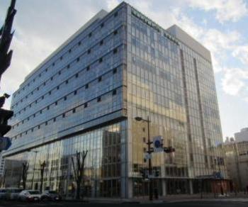 9階建てで外壁がガラス張りになっている建物を下から見上げるアングルで撮影した写真