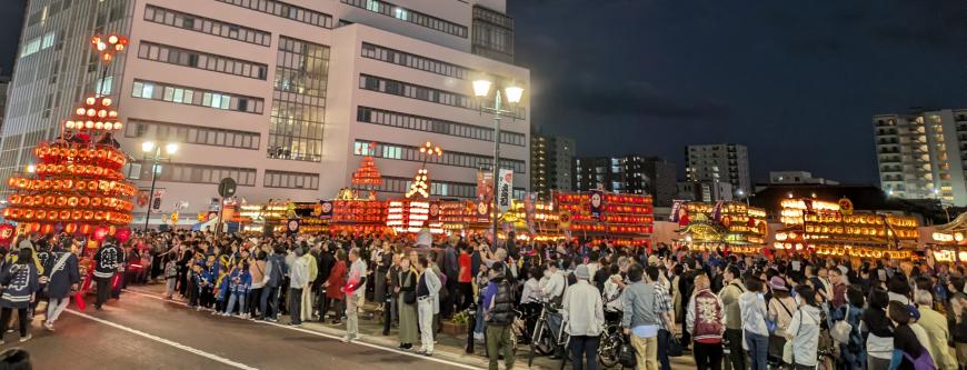 破風屋根の曳き山にたくさんの提灯が飾り付けられた連山車を見に訪れた多くの人々の写真