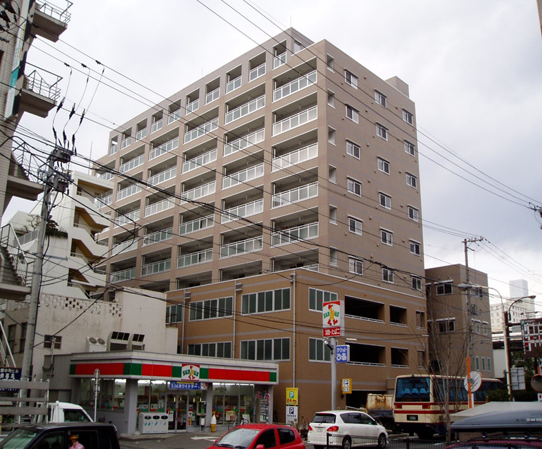 コンビニエンスストアが隣接しており、下階に駐車場がある茶色い外壁で10階建ての建物の外観写真